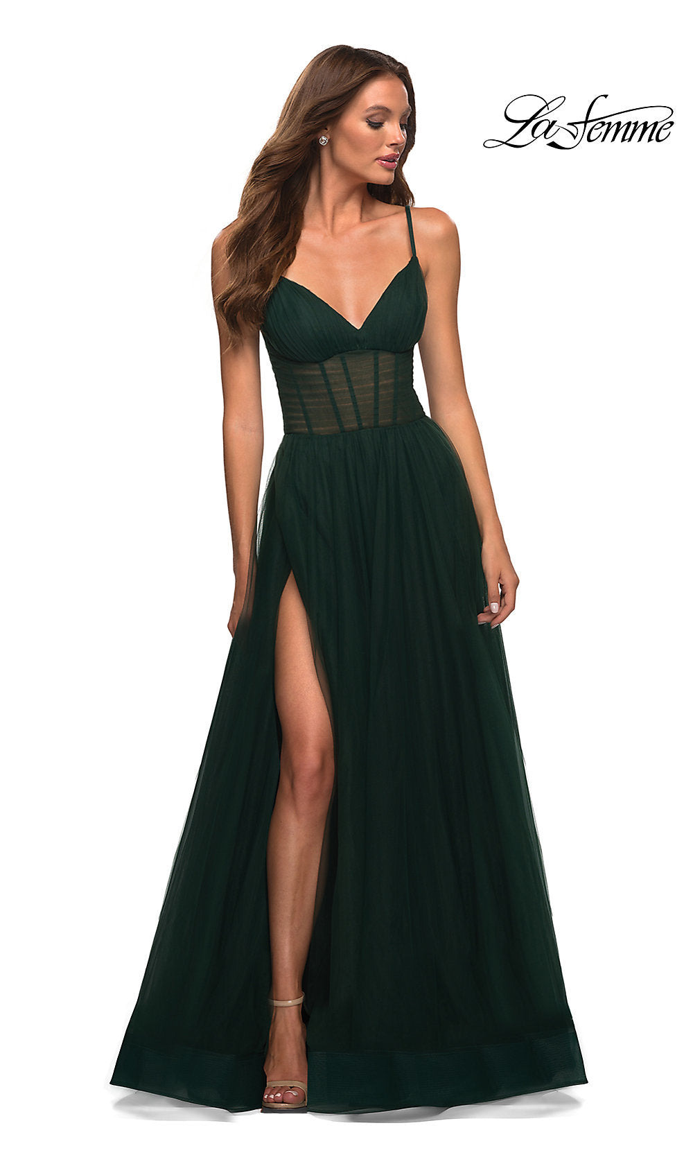 A woman stands looking to the side in a dark emerald Long La Femme Prom Dress featuring thin straps, a sheer corset waist, fitted bodice, and high side slit. The “La Femme†logo appears in the top right corner.