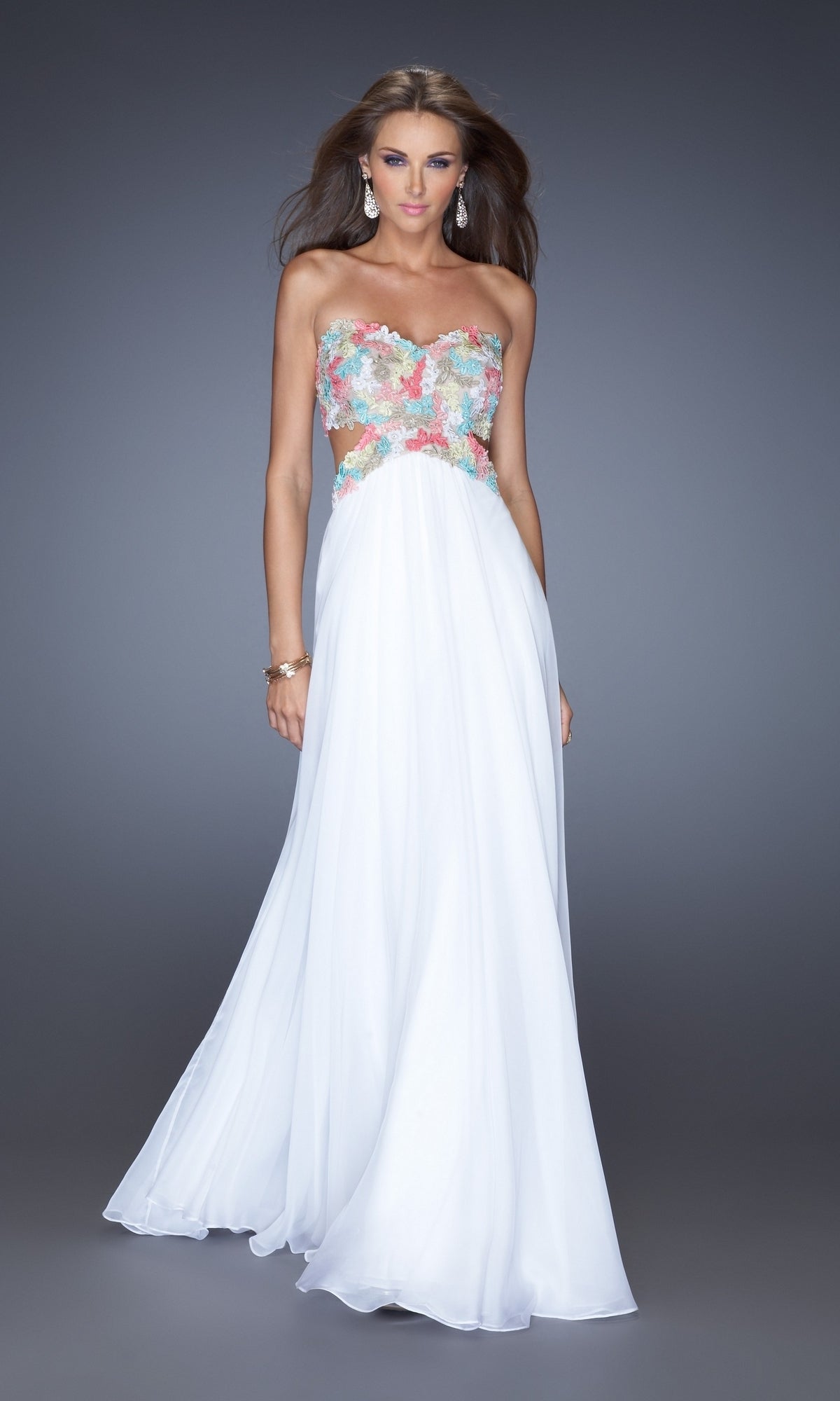 A woman models the La Femme Multicolor-Lace Chiffon Prom Dress 20059, featuring a strapless white design and colorful floral lace bodice, as she stands against a plain gray background.