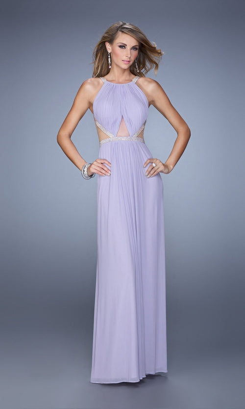 A woman wears the Long A-Line Prom Dress: La Femme 21145, an affordable, sleeveless, floor-length lavender gown with side cutouts and silver accents, standing against a plain gray background.