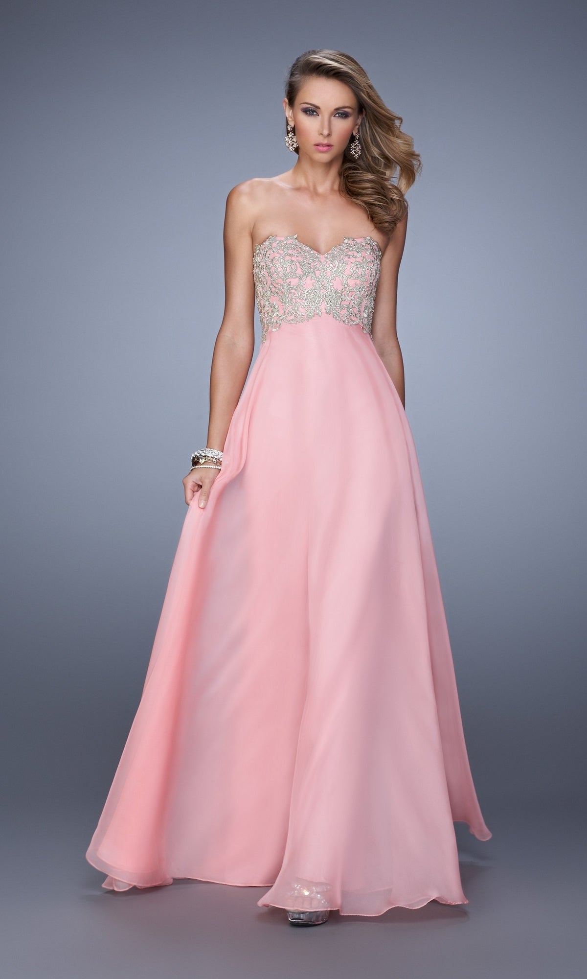 A woman wearing the La Femme Embroidered Chiffon Prom Dress 21289, featuring a strapless design and beaded embroidered bodice, poses against a plain gray background.