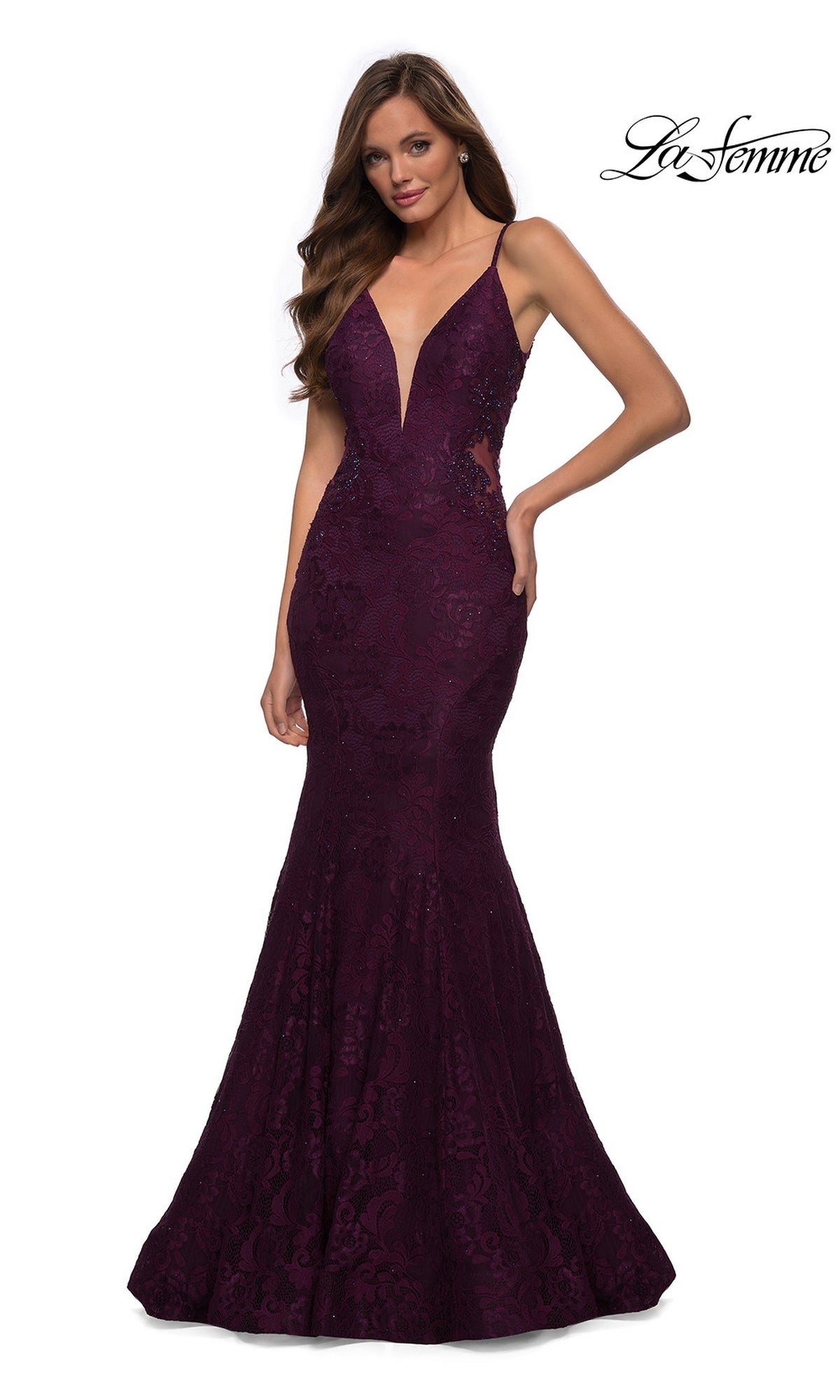 A woman wearing the La Femme Backless Long Lace Prom Dress 28355, featuring a sleeveless deep V-neck and mermaid skirt in dark purple, stands with one hand on her hip against a white background.