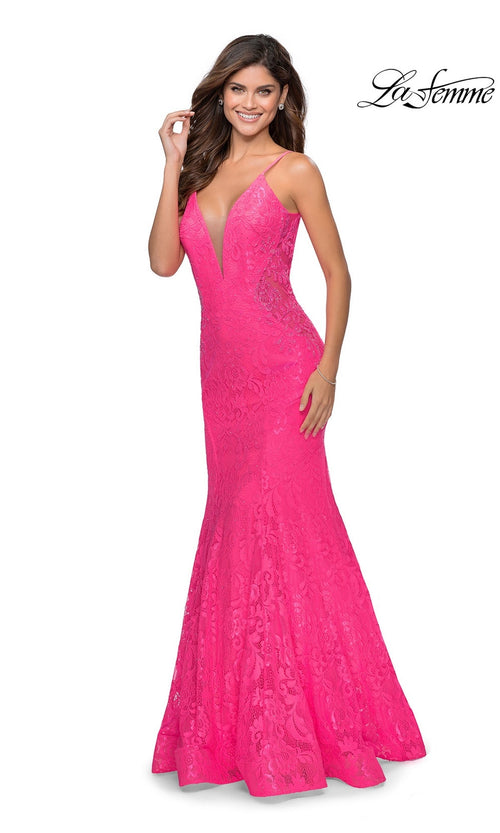 A woman in the La Femme Backless Long Lace Prom Dress 28355, featuring bright pink lace, thin straps, a deep V-neckline, and a mermaid skirt, smiles against a white background.