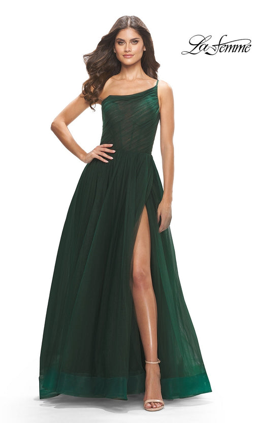 A woman poses gracefully in the One-Shoulder Sheer-Bodice Prom Ball Gown 31069, featuring a dark green hue and high slit, highlighting its elegant design against a white background.