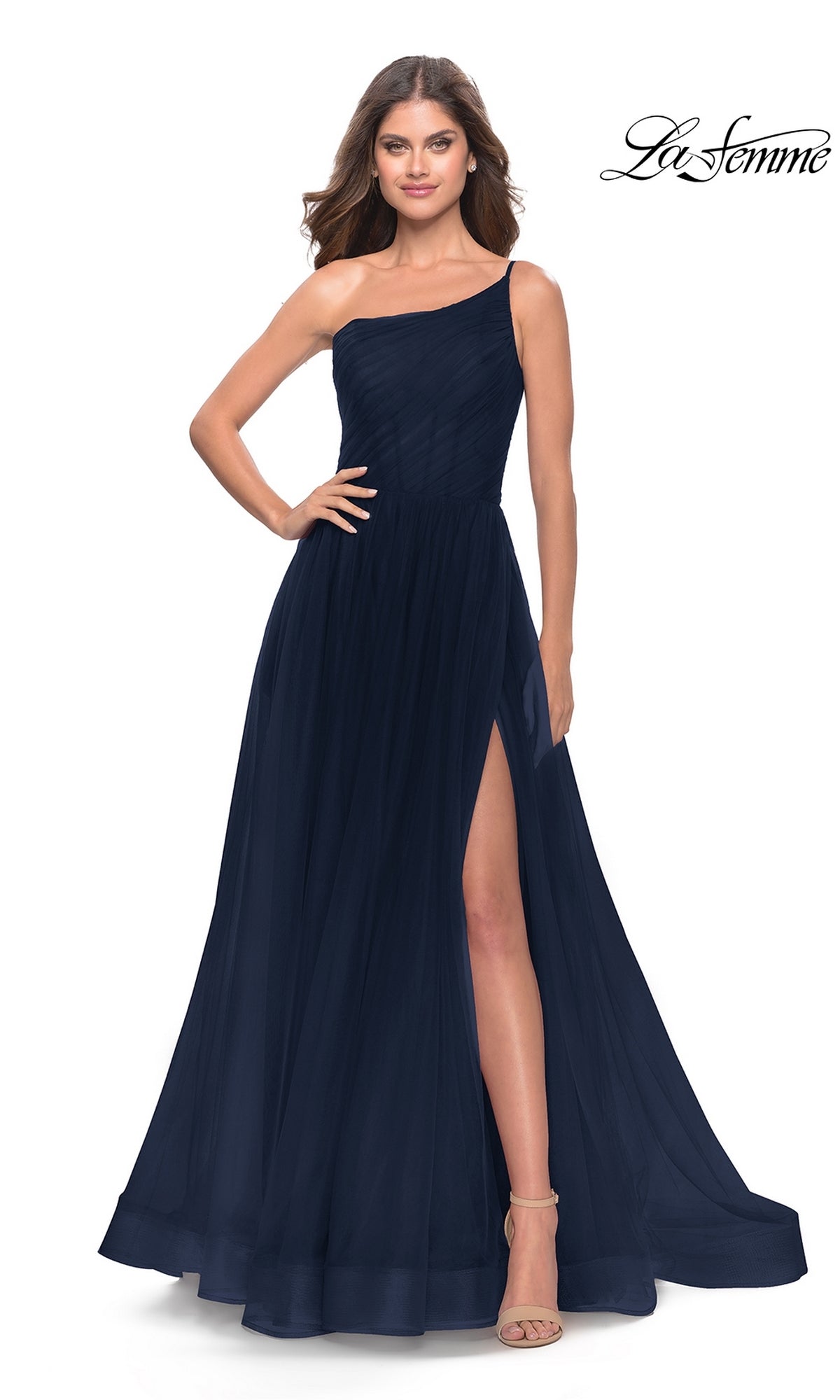 A woman stands confidently with one hand on her hip, wearing the One-Shoulder Sheer-Bodice Prom Ball Gown 31069â€”floor-length, dark navy, with a high leg slit.