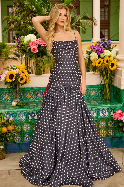 A woman stands outdoors before vibrant flowers, wearing the Long Prom Dress: Ava Presley 42368 in Black/White—a sleeveless, floor-length gown radiating timeless elegance.