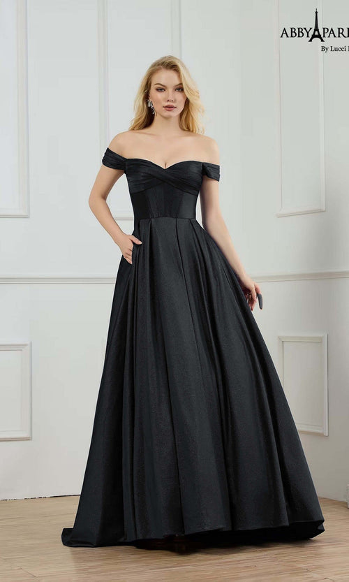 A woman in a black Abby Paris 90373 long prom dress with a fitted corset bodice stands in a minimalist, white-paneled room.